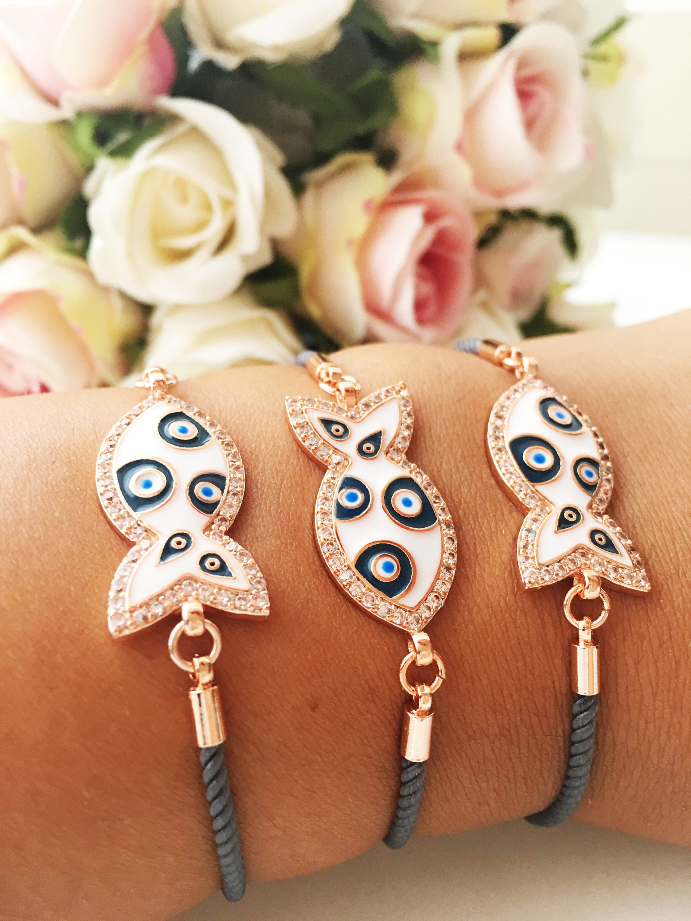A stylish Fish Charm Bracelet featuring a rose gold plated evil eye charm on an adjustable string, perfect for everyday wear.