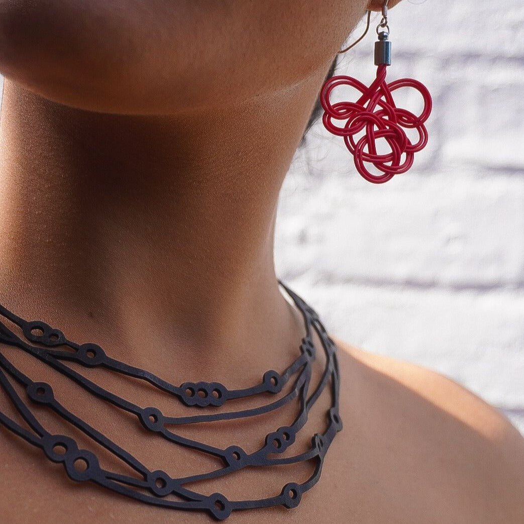 Flare Reclaimed Rubber Necklace made from recycled tyre inner tubes, featuring a multi-strap design and a button snap fastener.
