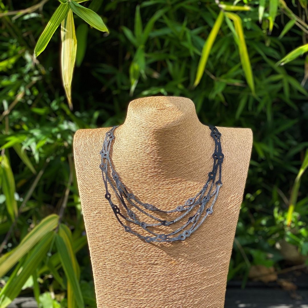 Flare Reclaimed Rubber Necklace made from recycled tyre inner tubes, featuring a multi-strap design and a button snap fastener.