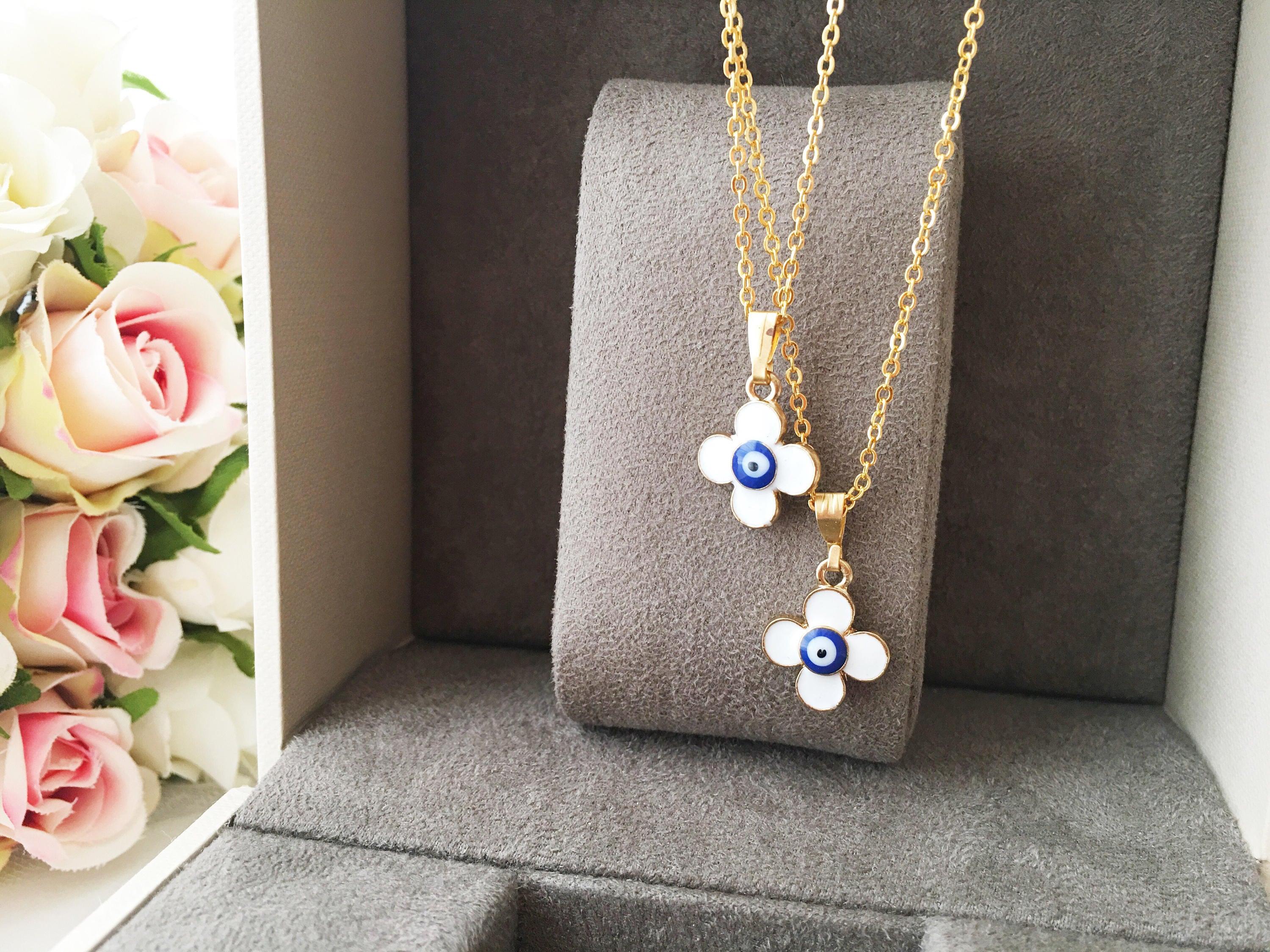Handmade four leaf clover necklace with a white evil eye charm on a gold plated chain, symbolizing protection and good luck.