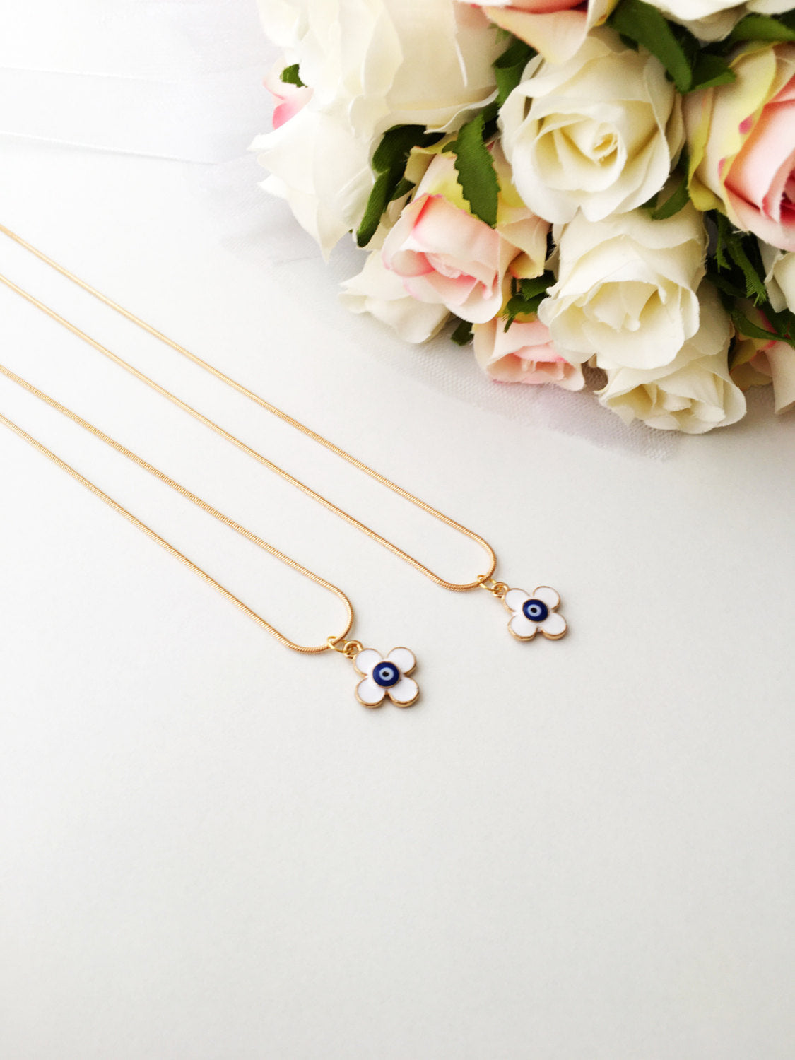 Handmade four leaf clover necklace with a white evil eye charm on a gold plated chain, symbolizing protection and good luck.