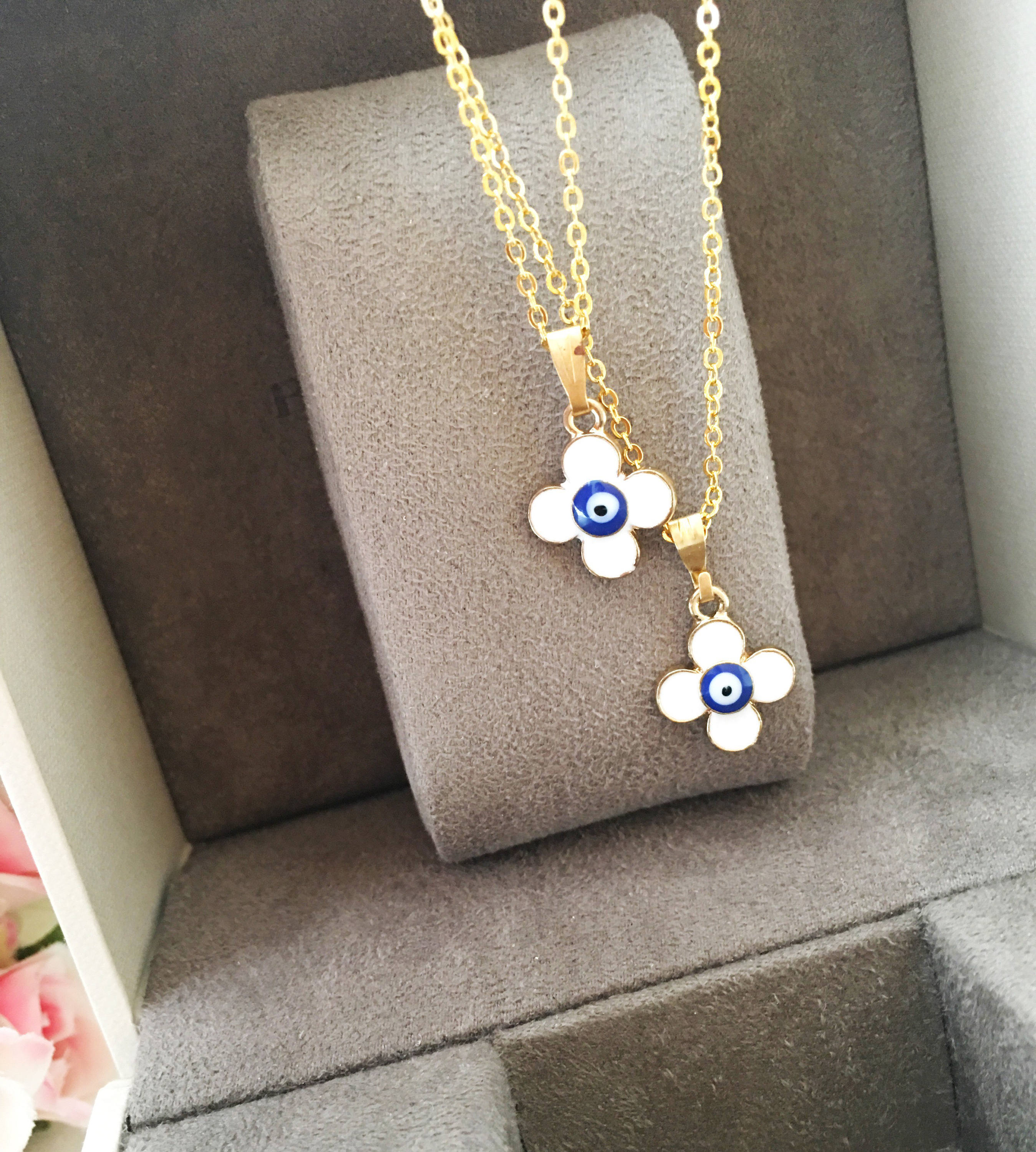 Handmade four leaf clover necklace with a white evil eye charm on a gold plated chain, symbolizing protection and good luck.