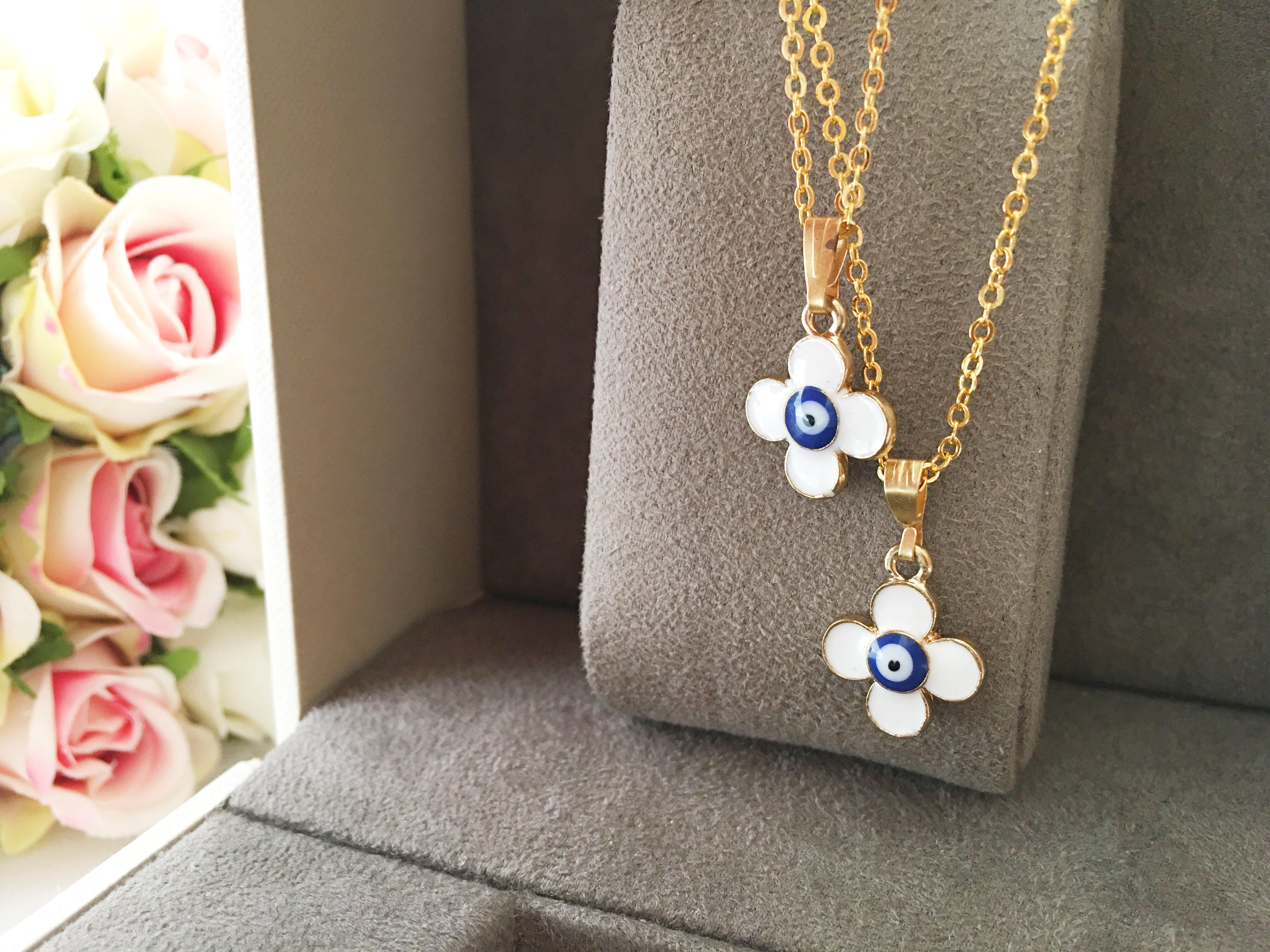 Handmade four leaf clover necklace with a white evil eye charm on a gold plated chain, symbolizing protection and good luck.
