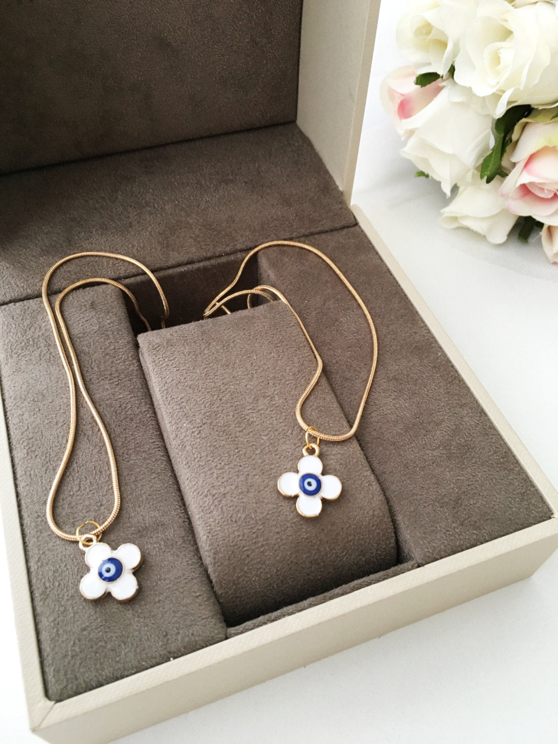 Handmade four leaf clover necklace with a white evil eye charm on a gold plated chain, symbolizing protection and good luck.