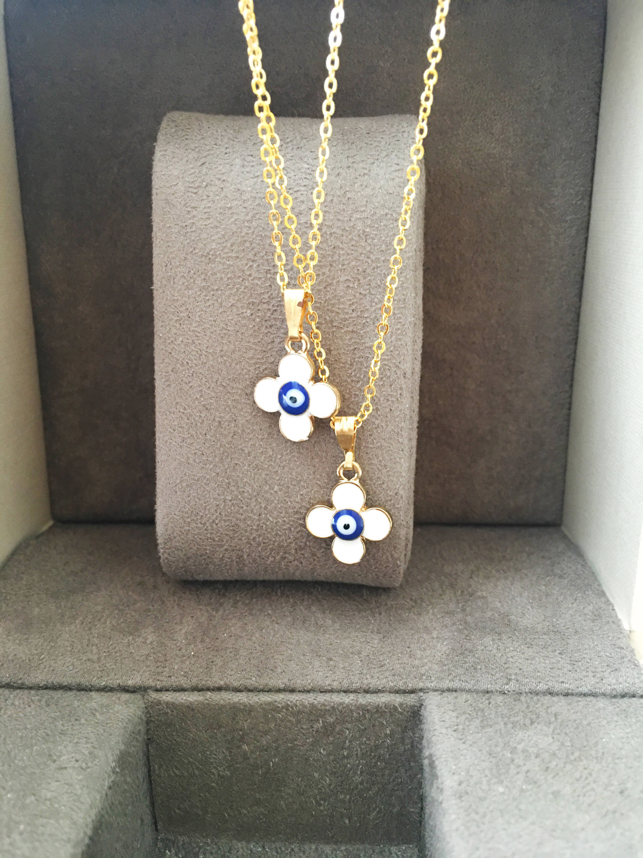 Handmade four leaf clover necklace with a white evil eye charm on a gold plated chain, symbolizing protection and good luck.