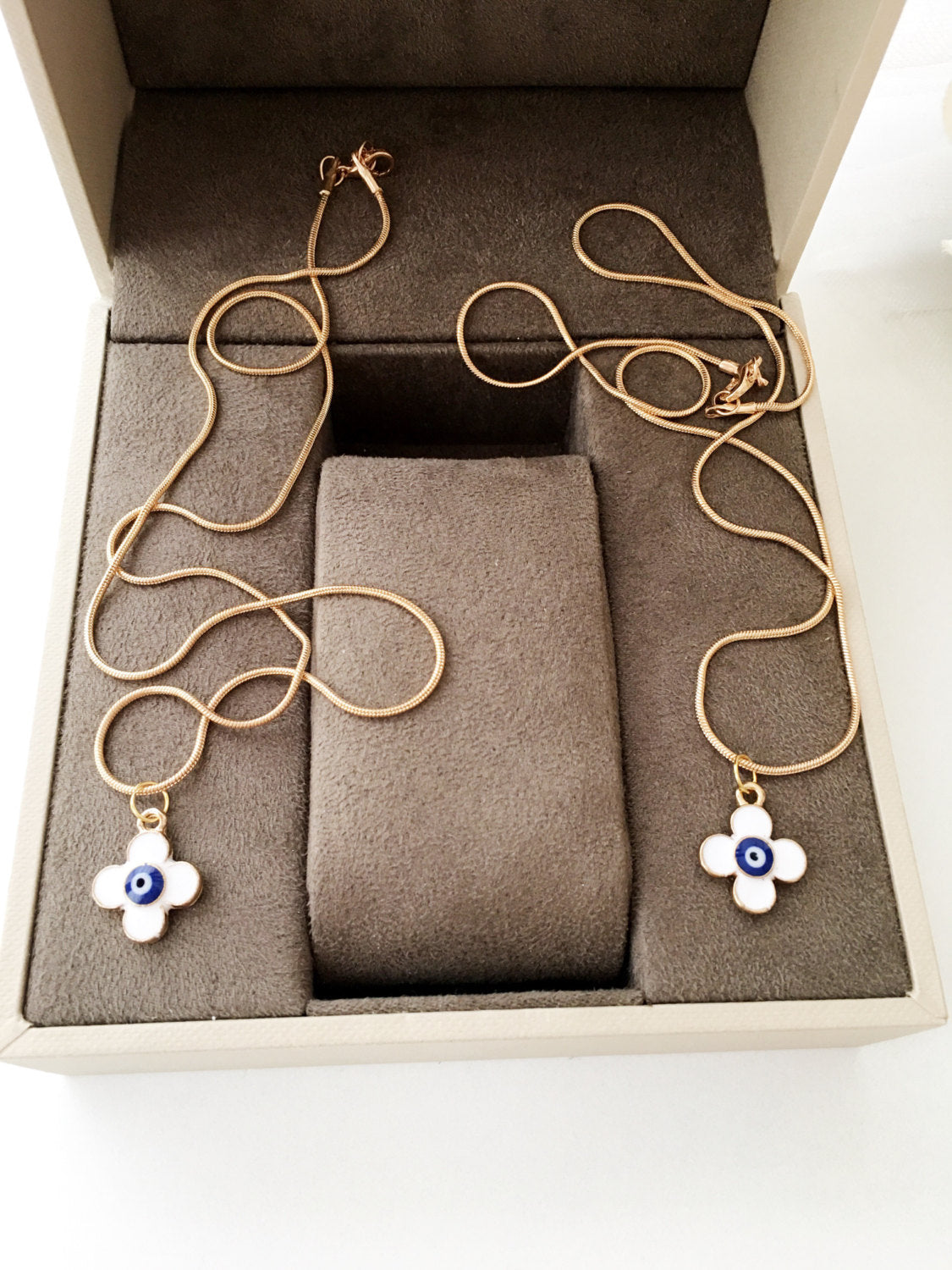 Handmade four leaf clover necklace with a white evil eye charm on a gold plated chain, symbolizing protection and good luck.