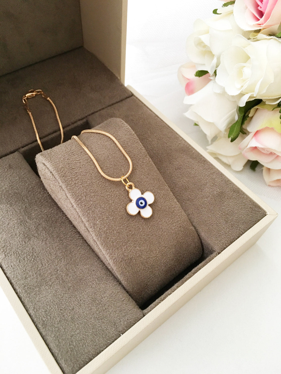 Handmade four leaf clover necklace with a white evil eye charm on a gold plated chain, symbolizing protection and good luck.