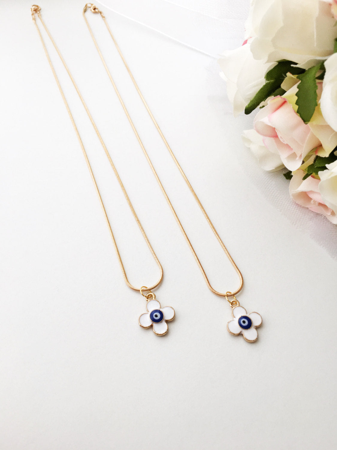Handmade four leaf clover necklace with a white evil eye charm on a gold plated chain, symbolizing protection and good luck.
