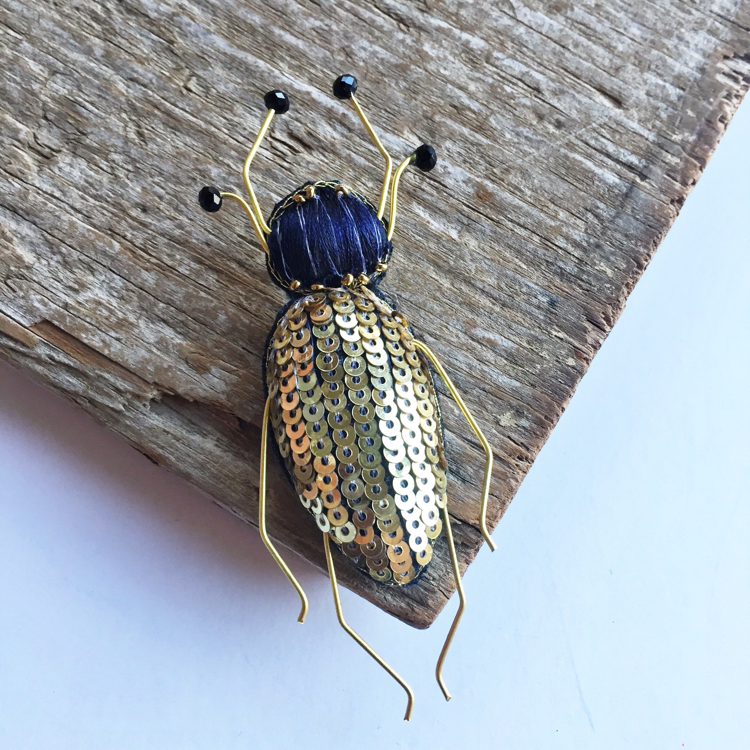 A handcrafted Francis Bug Brooch featuring vibrant colors and intricate details, showcasing a whimsical insect design made from seed beads and silk.