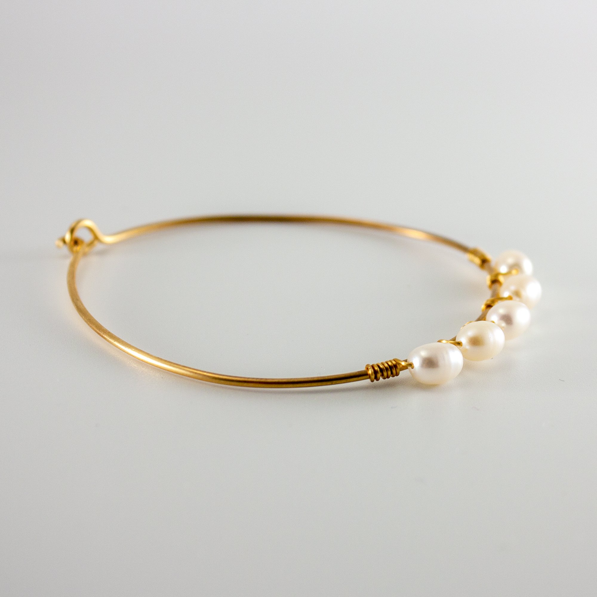 Elegant Freshwater Rice Pearl Wrapped Gold Bangle featuring five ivory pearls on a gold brass band, perfect for chic styling.