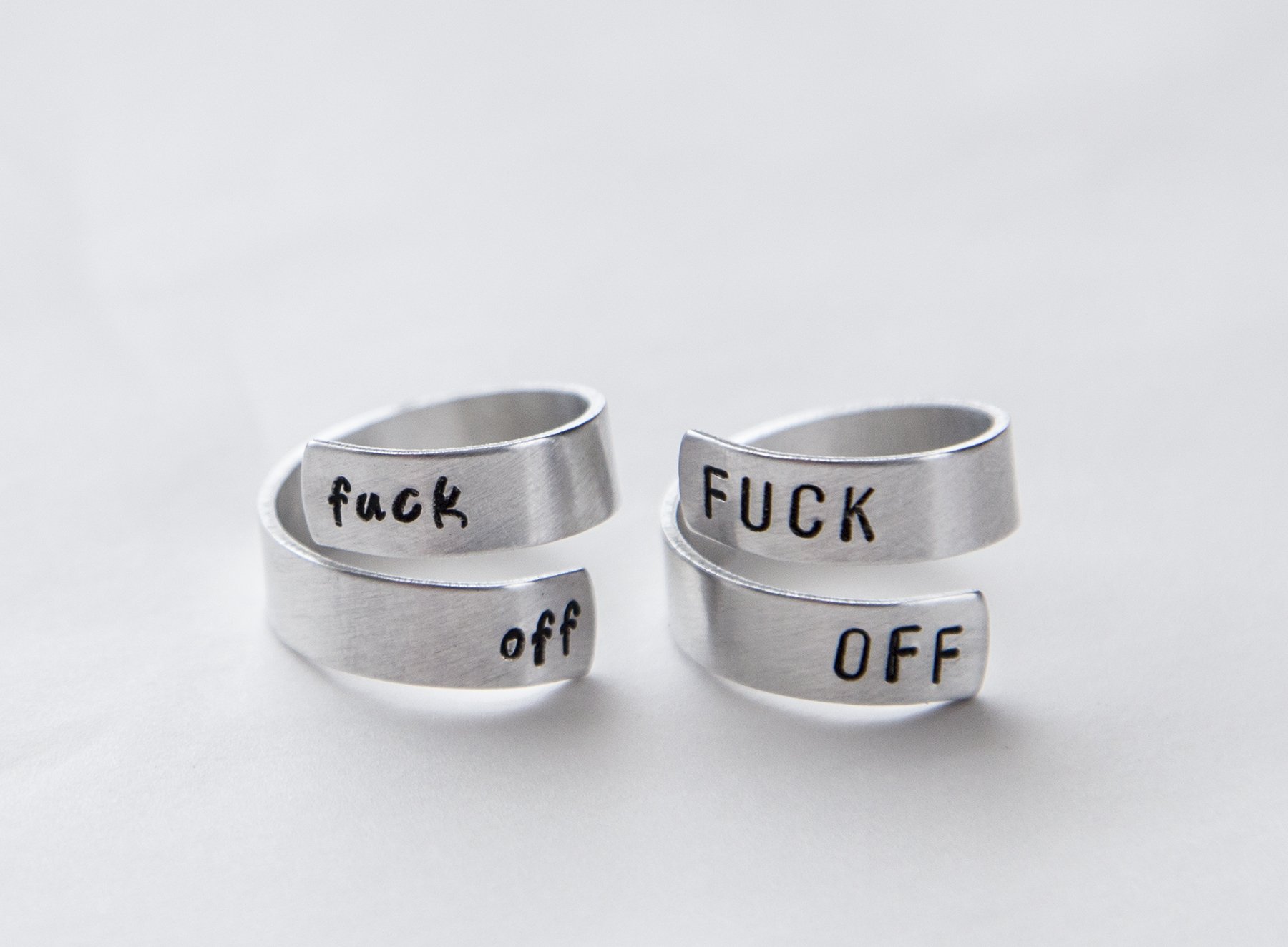 A stylish adjustable aluminum ring with the words 'Fuck Off' hand-stamped, showcasing a unique and bold feminist statement.