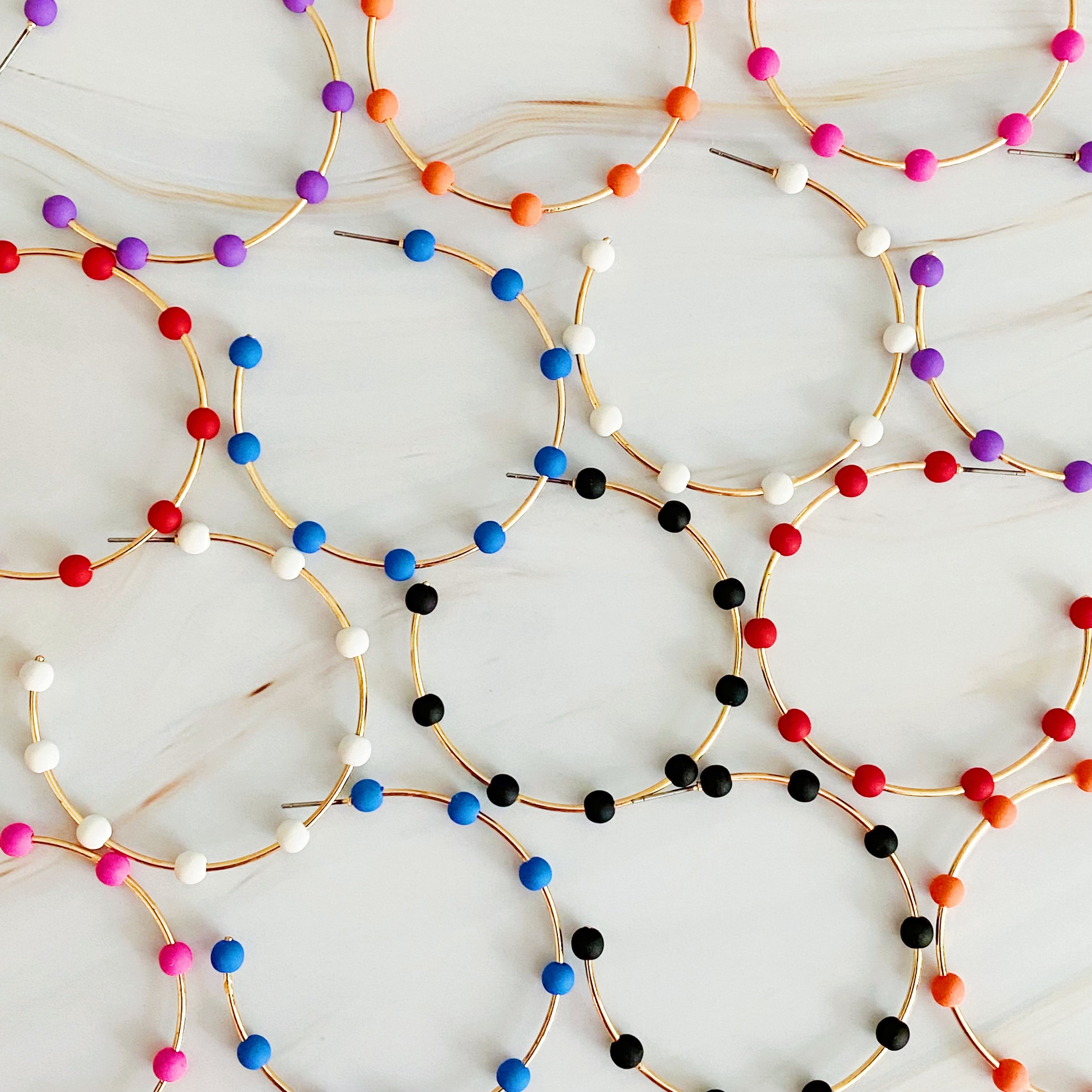 Games On Cloud Nine Hoop Earrings featuring a slim golden hoop with nine colorful rubber ball beads, perfect for game day.