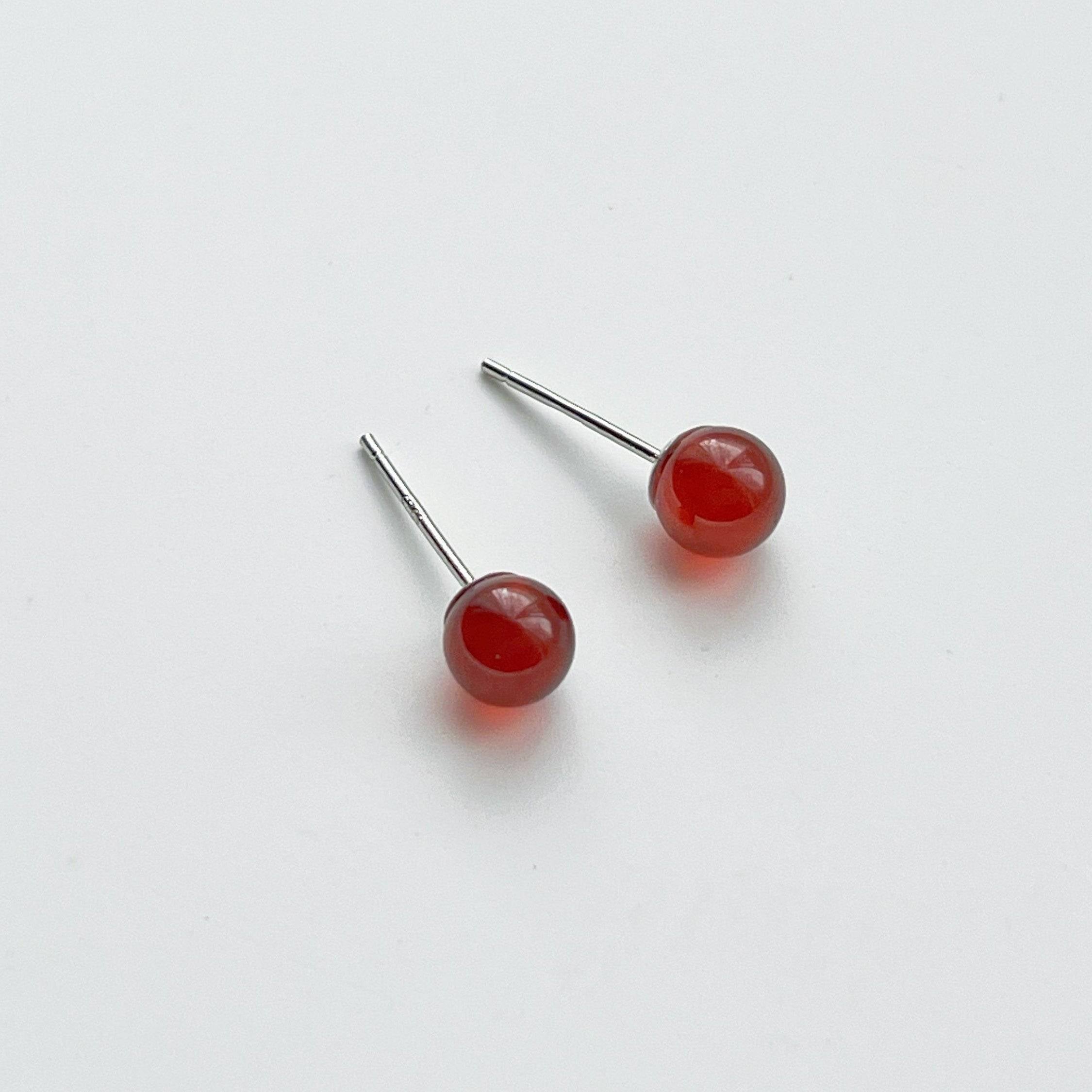 A pair of dark red garnet stud earrings set in sterling silver, showcasing their natural beauty and unique characteristics.
