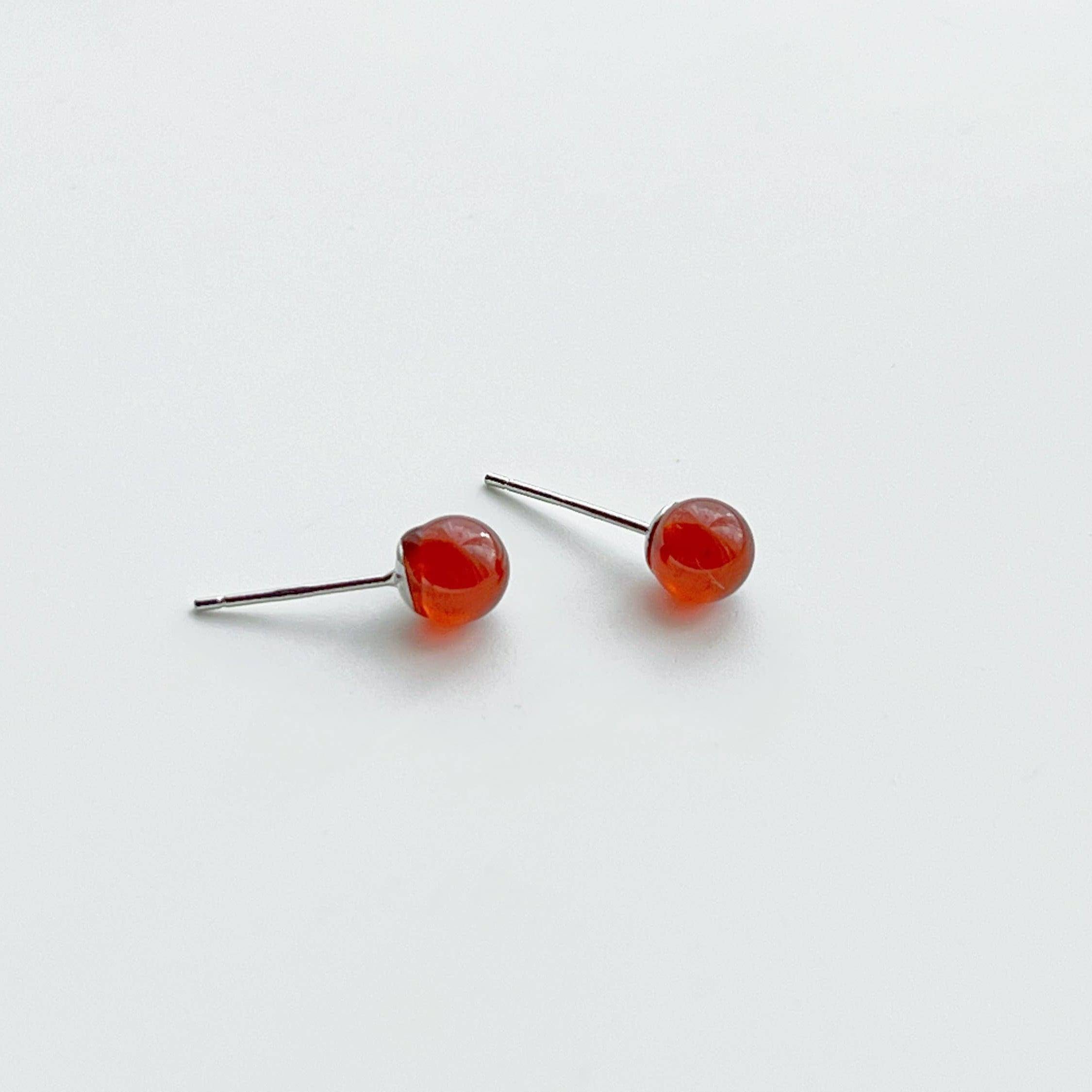 A pair of dark red garnet stud earrings set in sterling silver, showcasing their natural beauty and unique characteristics.