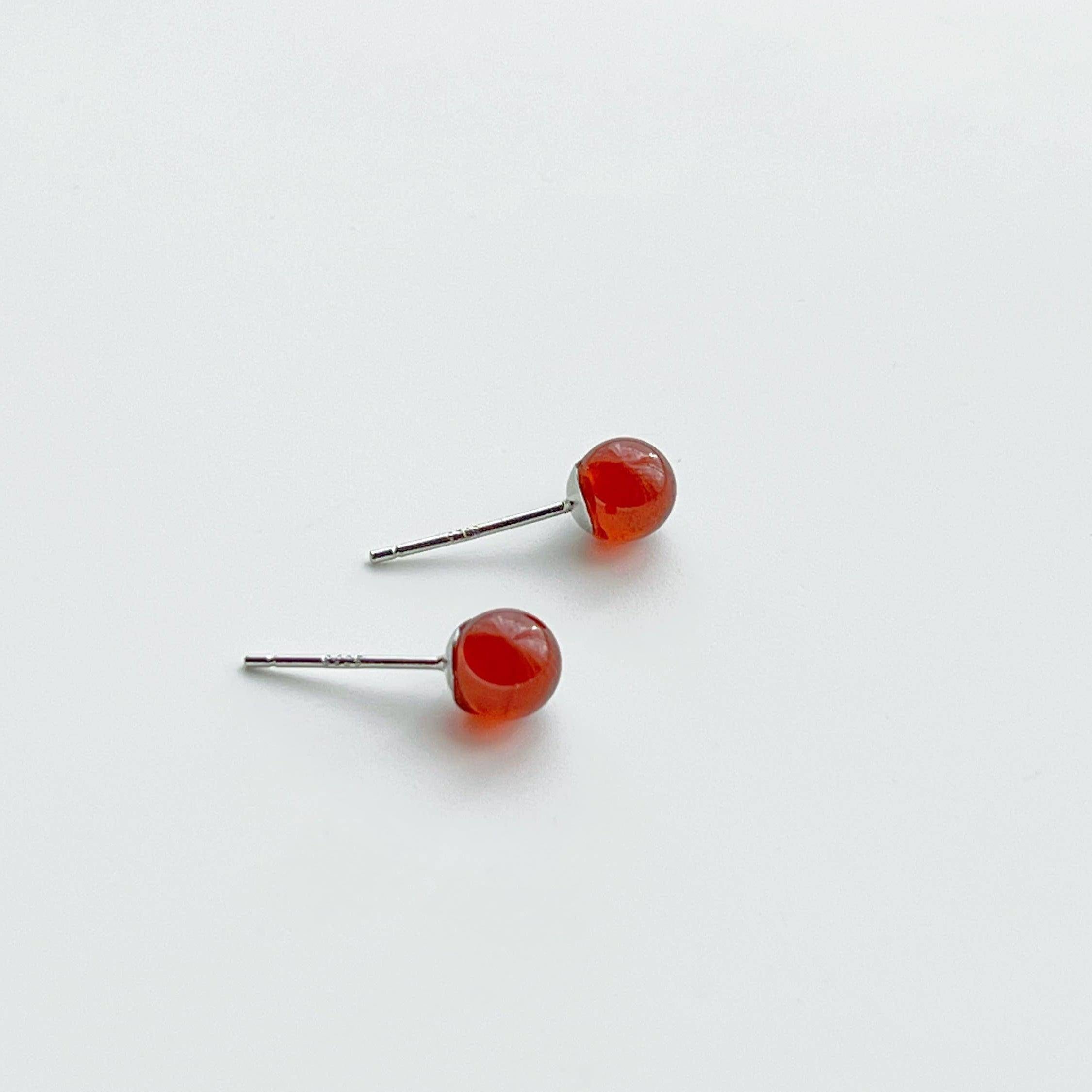 A pair of dark red garnet stud earrings set in sterling silver, showcasing their natural beauty and unique characteristics.