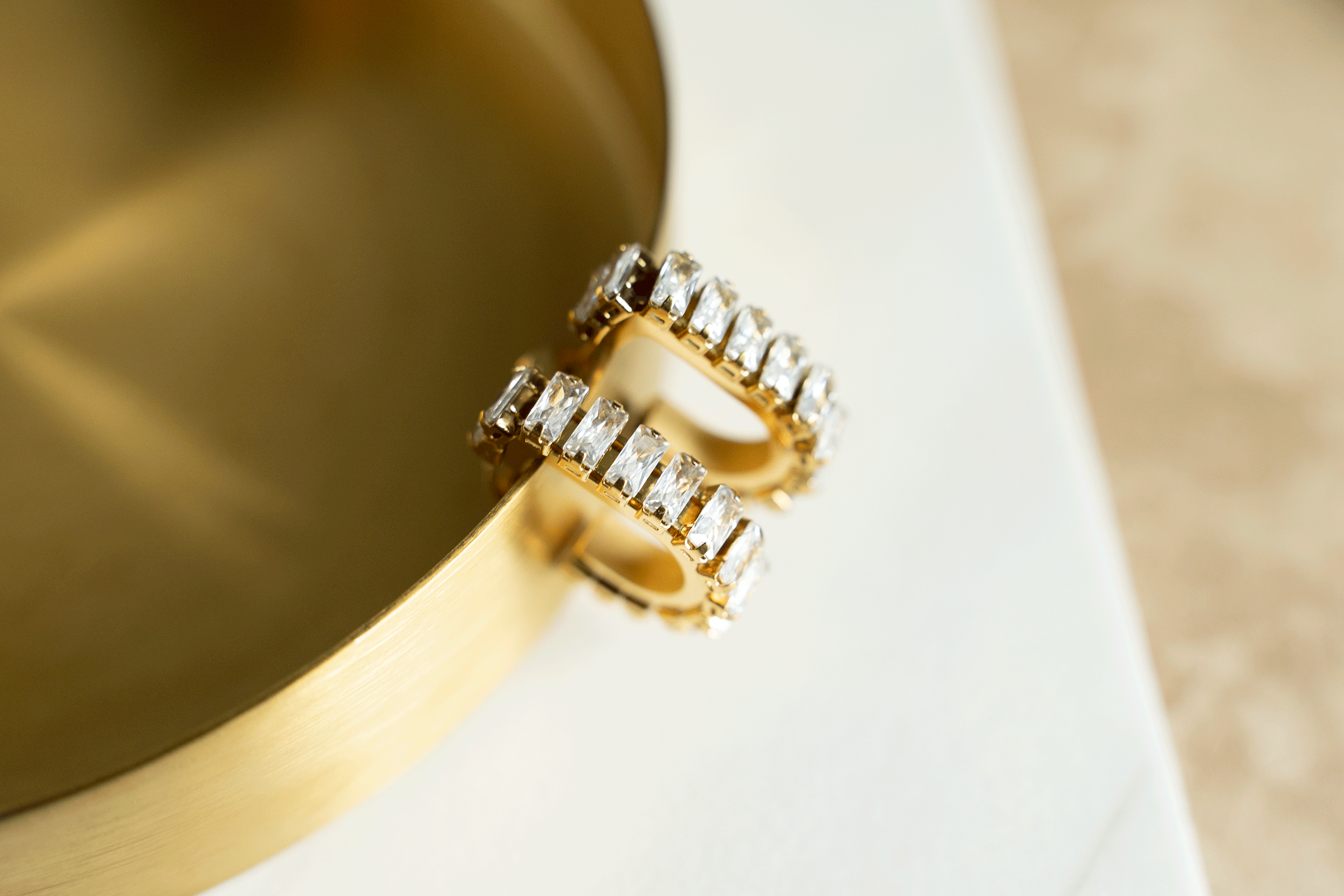 GEMMA Hoops featuring 18k gold plated stainless steel with baguette cut stones in a geometric u-shaped design.