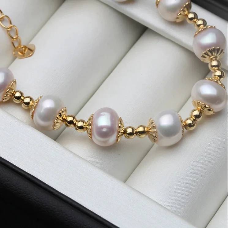 A beautiful Genuine Freshwater White Pearl Bracelet featuring white pearls and gold accents, elegantly displayed on a soft surface.
