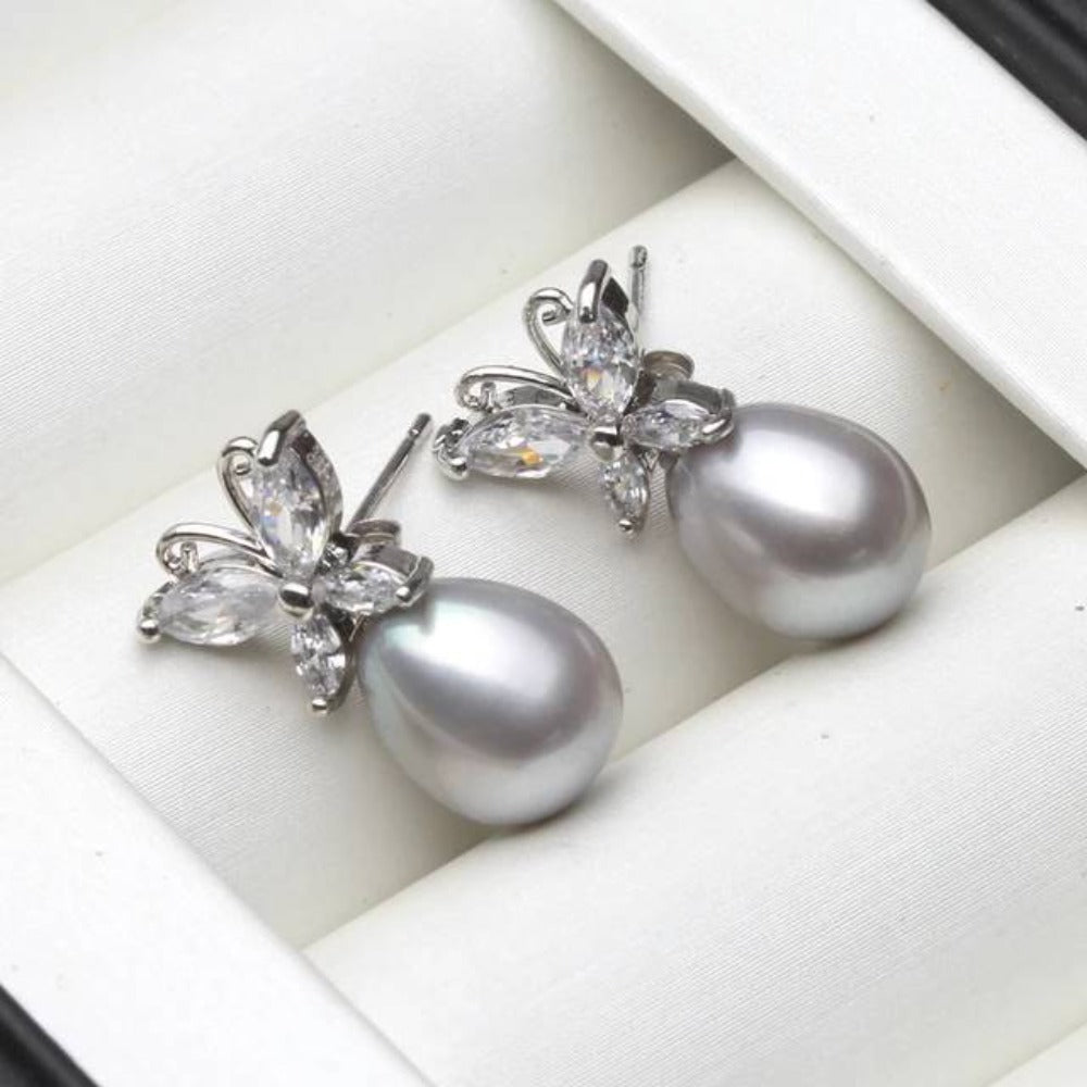 Elegant butterfly stud earrings featuring genuine white freshwater pearls and simulated diamonds, showcasing a delicate design.