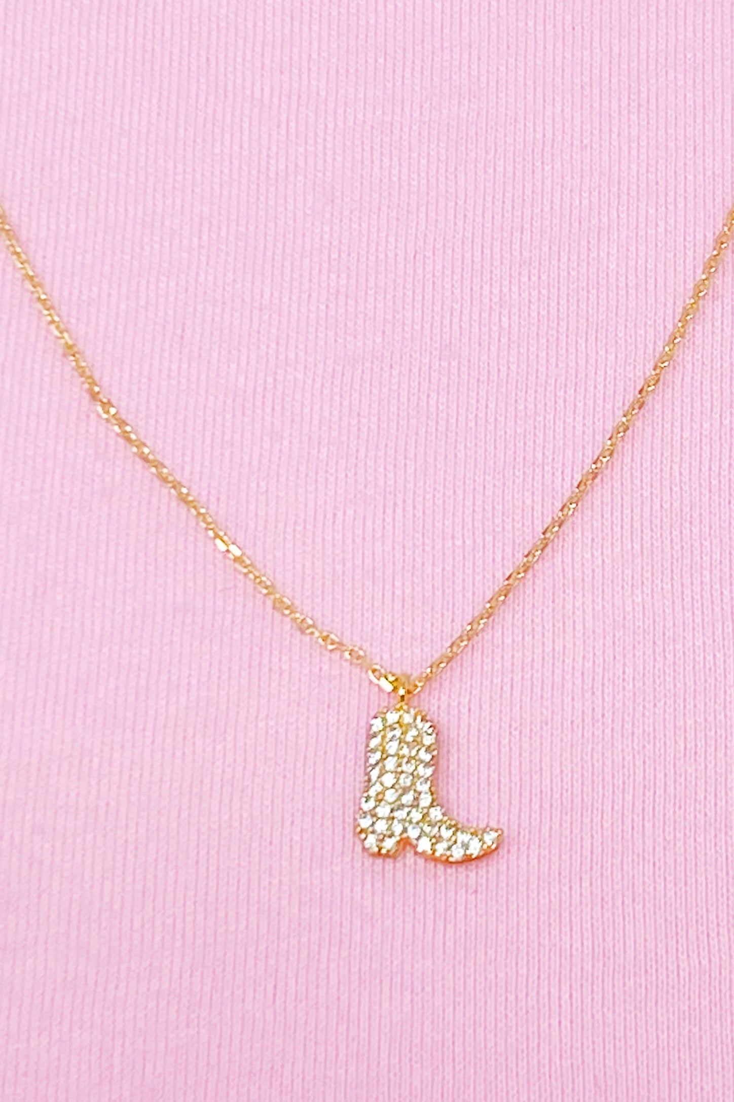 A detailed gold plated brass cowgirl boot necklace with a 16-inch chain and 2-inch extender, showcasing its dainty design.