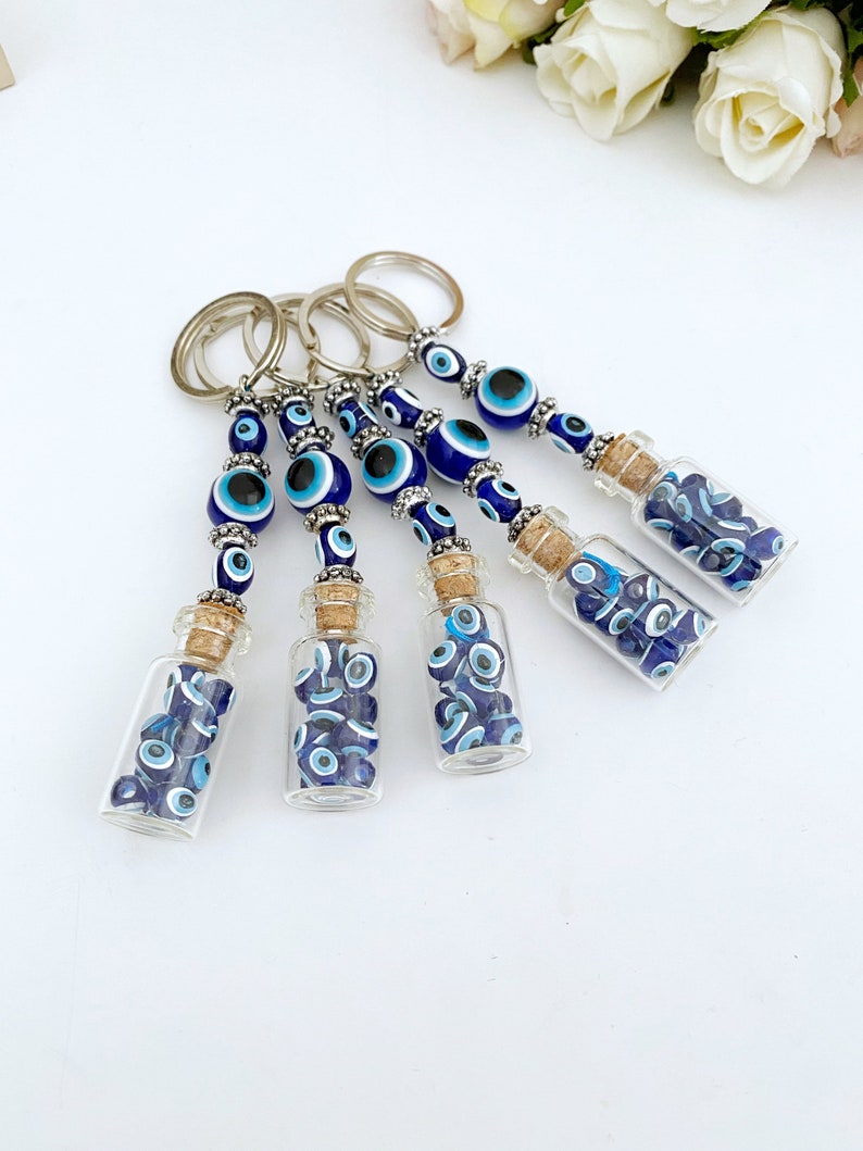 A beautiful blue glass evil eye bottle keychain, symbolizing protection and luck, featuring intricate details and a shiny finish.