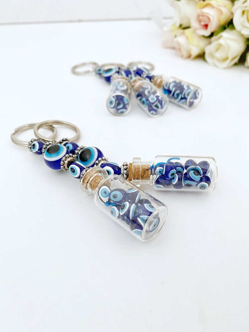 A beautiful blue glass evil eye bottle keychain, symbolizing protection and luck, featuring intricate details and a shiny finish.