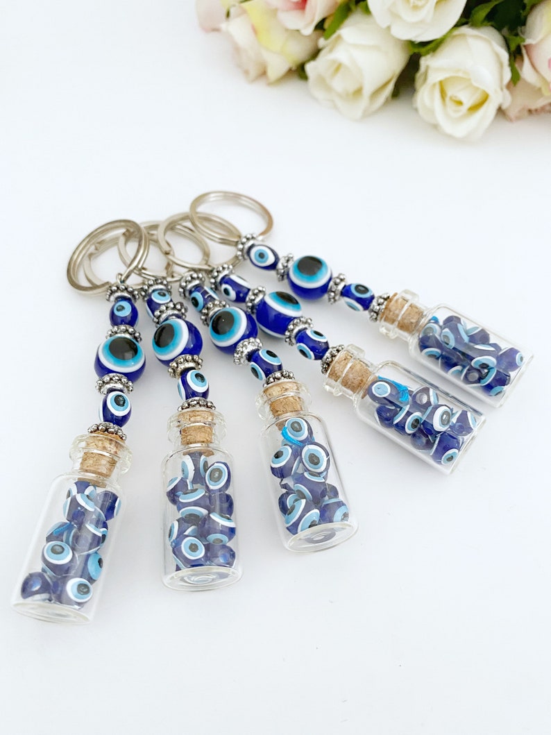 A beautiful blue glass evil eye bottle keychain, symbolizing protection and luck, featuring intricate details and a shiny finish.