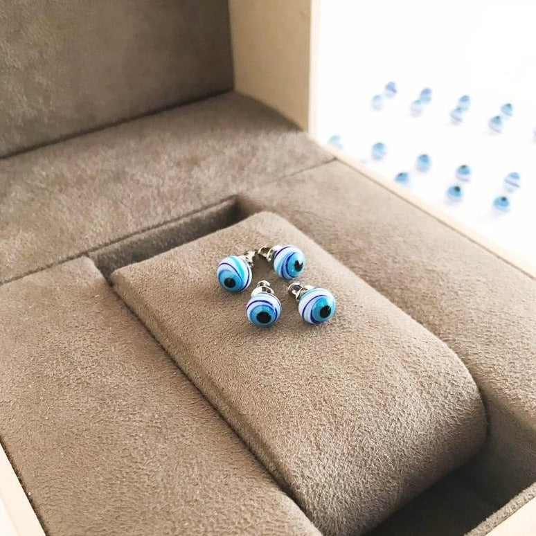 A pair of handmade Glass Evil Eye Stud Earrings featuring an 8mm blue evil eye bead with silver finishing, symbolizing protection.
