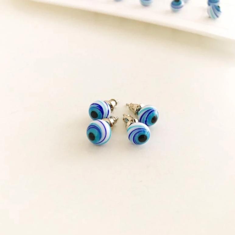 A pair of handmade Glass Evil Eye Stud Earrings featuring an 8mm blue evil eye bead with silver finishing, symbolizing protection.