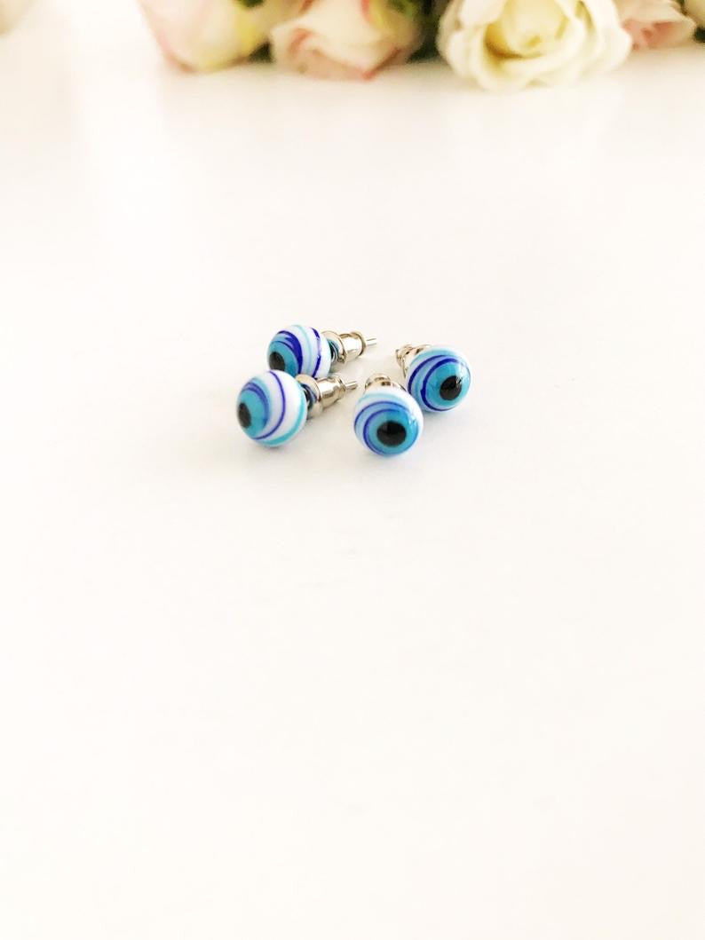 A pair of handmade Glass Evil Eye Stud Earrings featuring an 8mm blue evil eye bead with silver finishing, symbolizing protection.