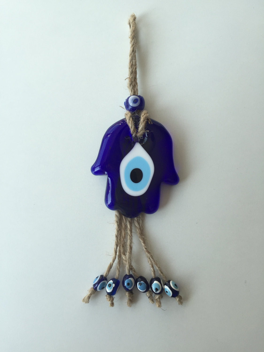 Handmade glass blue hamsa hand wall hanging with macramé design, symbolizing protection and good fortune.