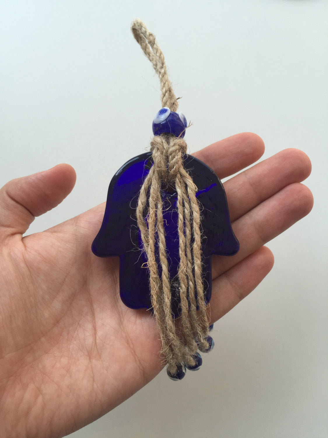 Handmade glass blue hamsa hand wall hanging with macramé design, symbolizing protection and good fortune.