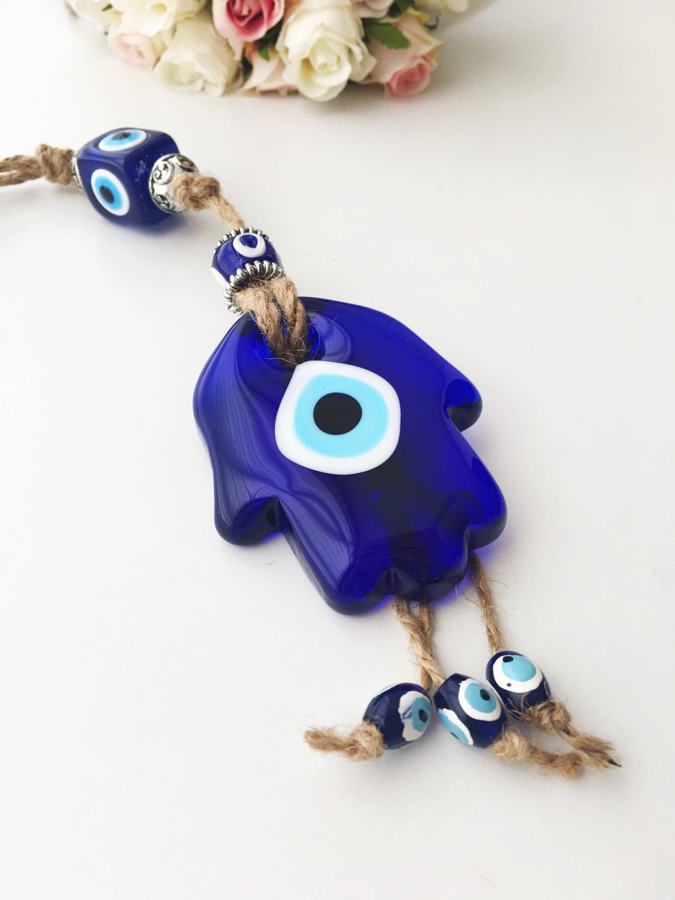 A beautifully crafted Glass Hamsa Evil Eye Wall Hanging featuring intricate macrame and a protective evil eye symbol, handmade in Turkey.
