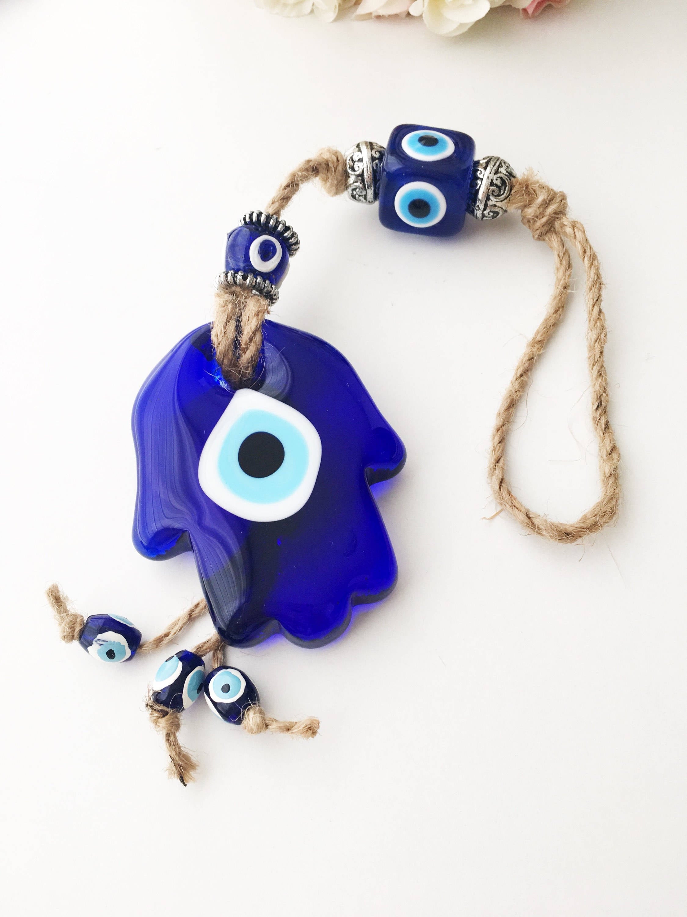 A beautifully crafted Glass Hamsa Evil Eye Wall Hanging featuring intricate macrame and a protective evil eye symbol, handmade in Turkey.