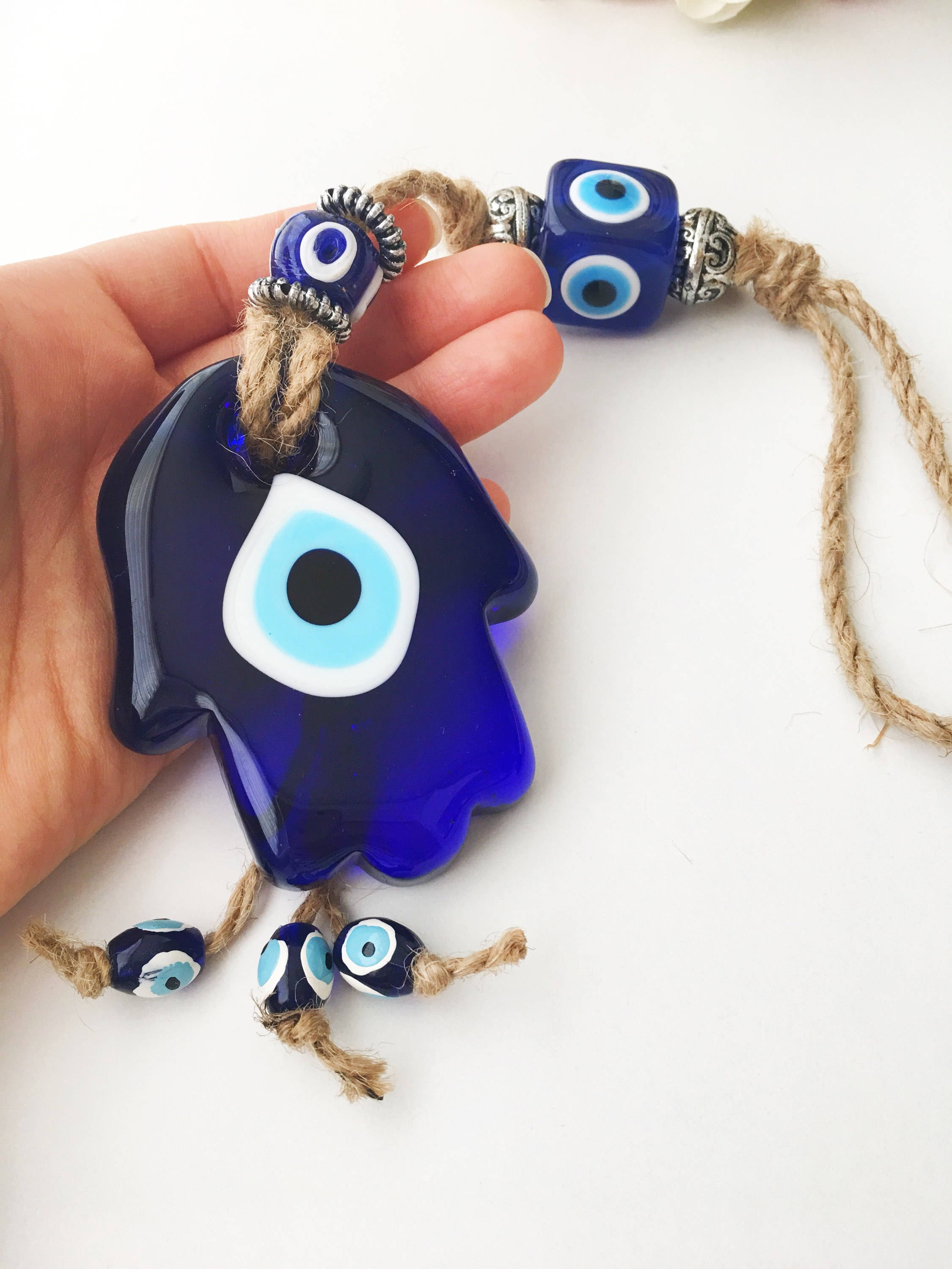 A beautifully crafted Glass Hamsa Evil Eye Wall Hanging featuring intricate macrame and a protective evil eye symbol, handmade in Turkey.
