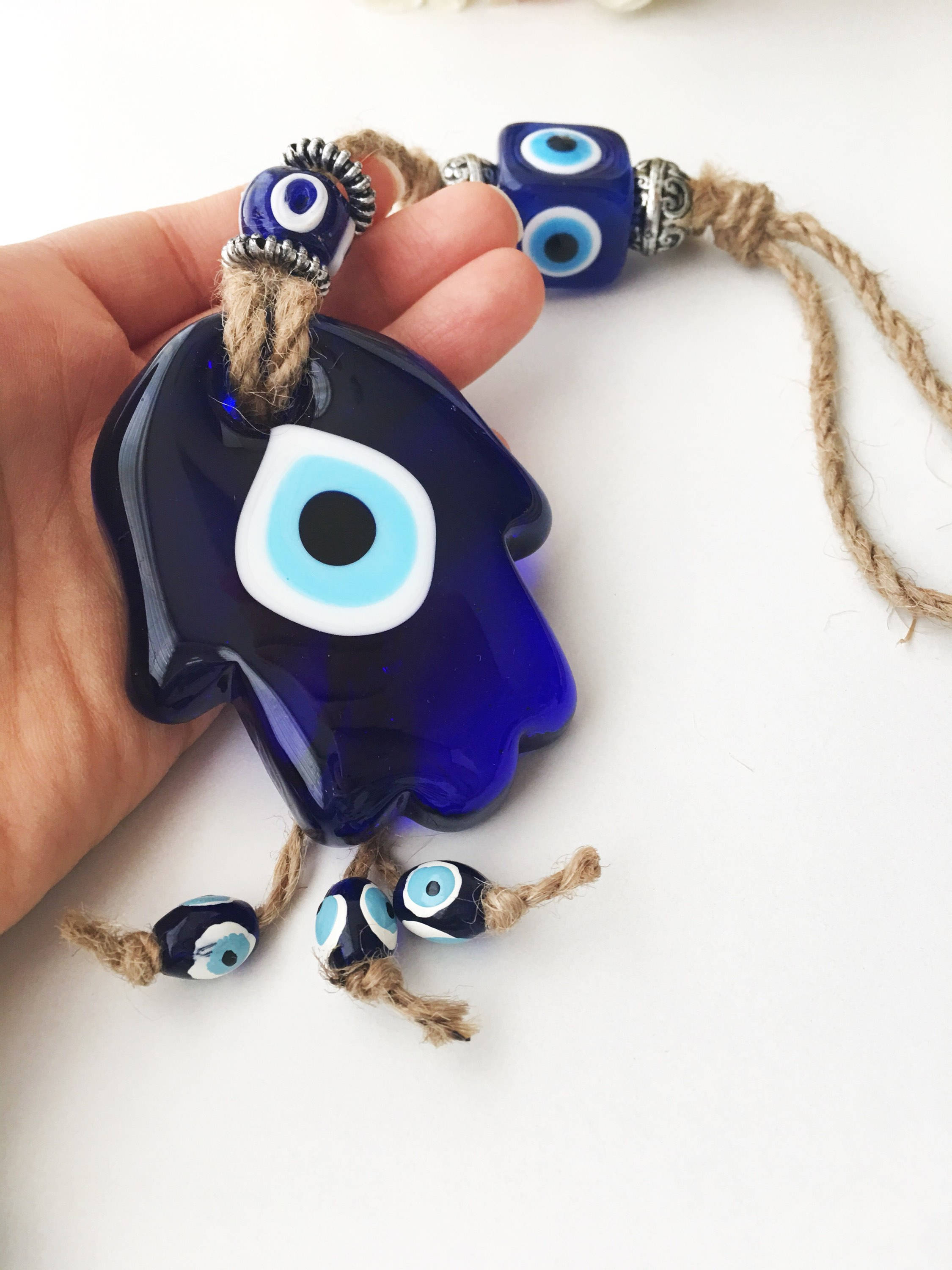A beautifully crafted Glass Hamsa Evil Eye Wall Hanging featuring intricate macrame and a protective evil eye symbol, handmade in Turkey.