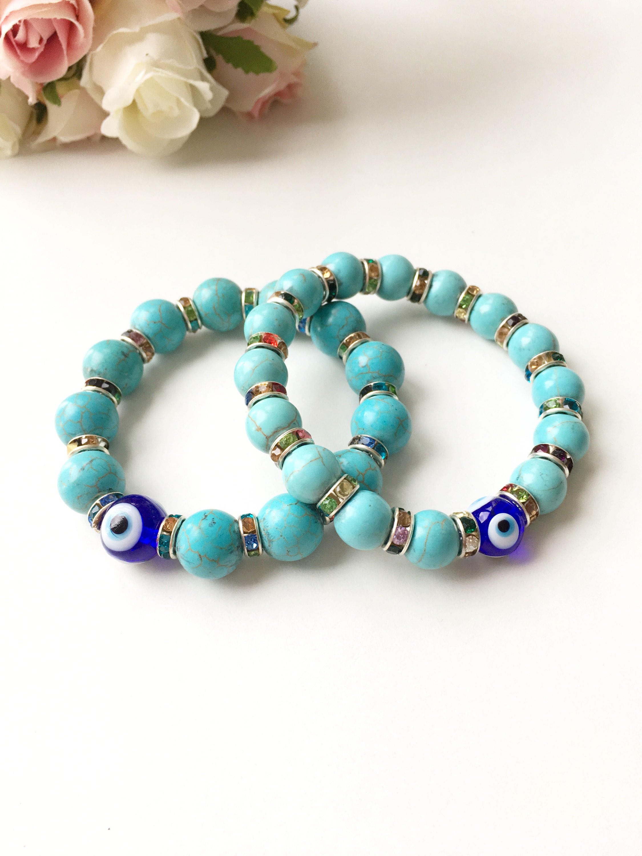A beautiful glass turquoise bead bracelet featuring a blue evil eye charm, showcasing vibrant colors and a stretch design for comfort.