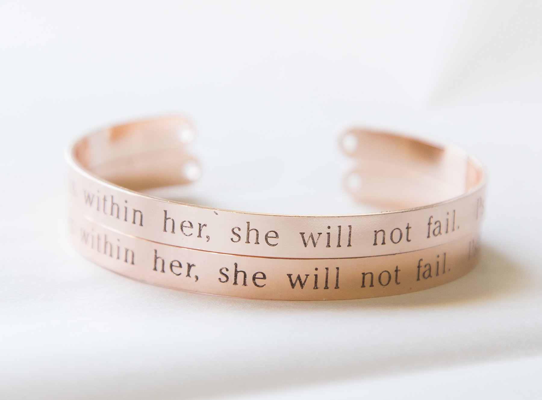 A delicate adjustable cuff bracelet engraved with 'God is Within Her She Will Not Fail', showcasing its inspirational message and elegant design.