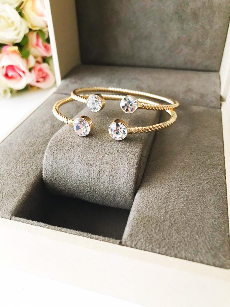 A beautiful gold bangle bracelet featuring turquoise and crystal beads, with a movable evil eye charm, showcasing its elegant design.