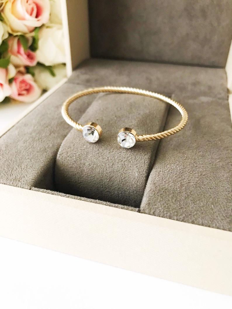 A beautiful gold bangle bracelet featuring turquoise and crystal beads, with a movable evil eye charm, showcasing its elegant design.