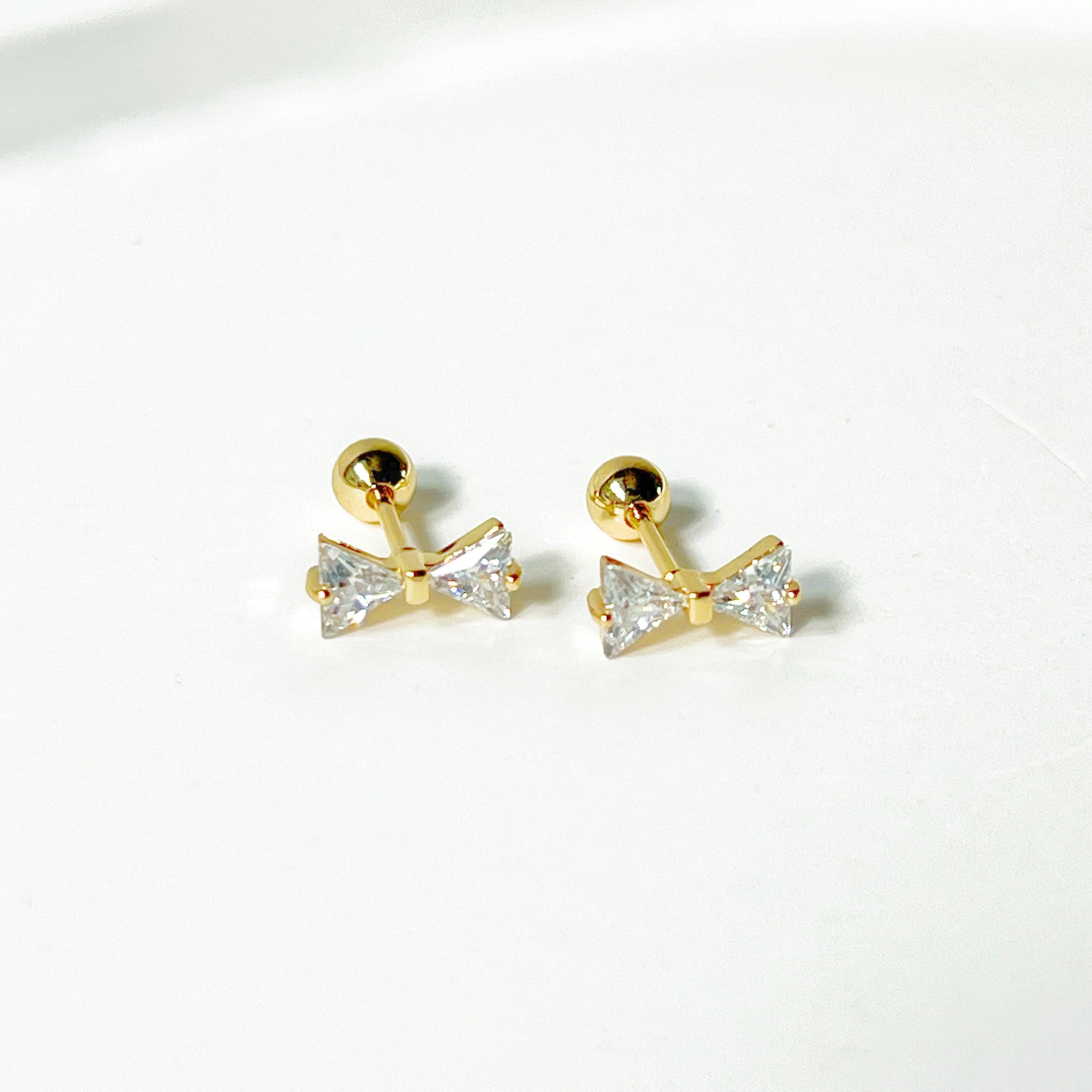 Gold Bow Zircon Earrings featuring a small bow design with clear zircon stones, set on a hypoallergenic surgical steel base.