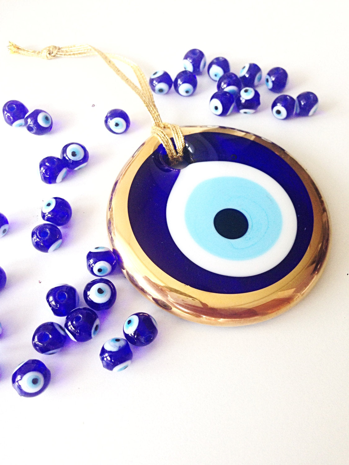 A 10cm gold evil eye bead wall hanging with blue rope, showcasing intricate handmade design and vibrant colors.