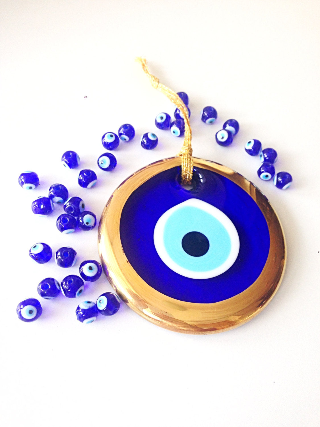 A 10cm gold evil eye bead wall hanging with blue rope, showcasing intricate handmade design and vibrant colors.