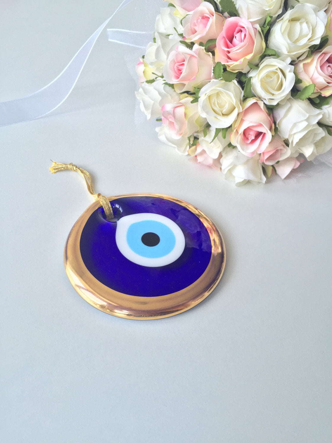 A 10cm gold evil eye bead wall hanging with blue rope, showcasing intricate handmade design and vibrant colors.