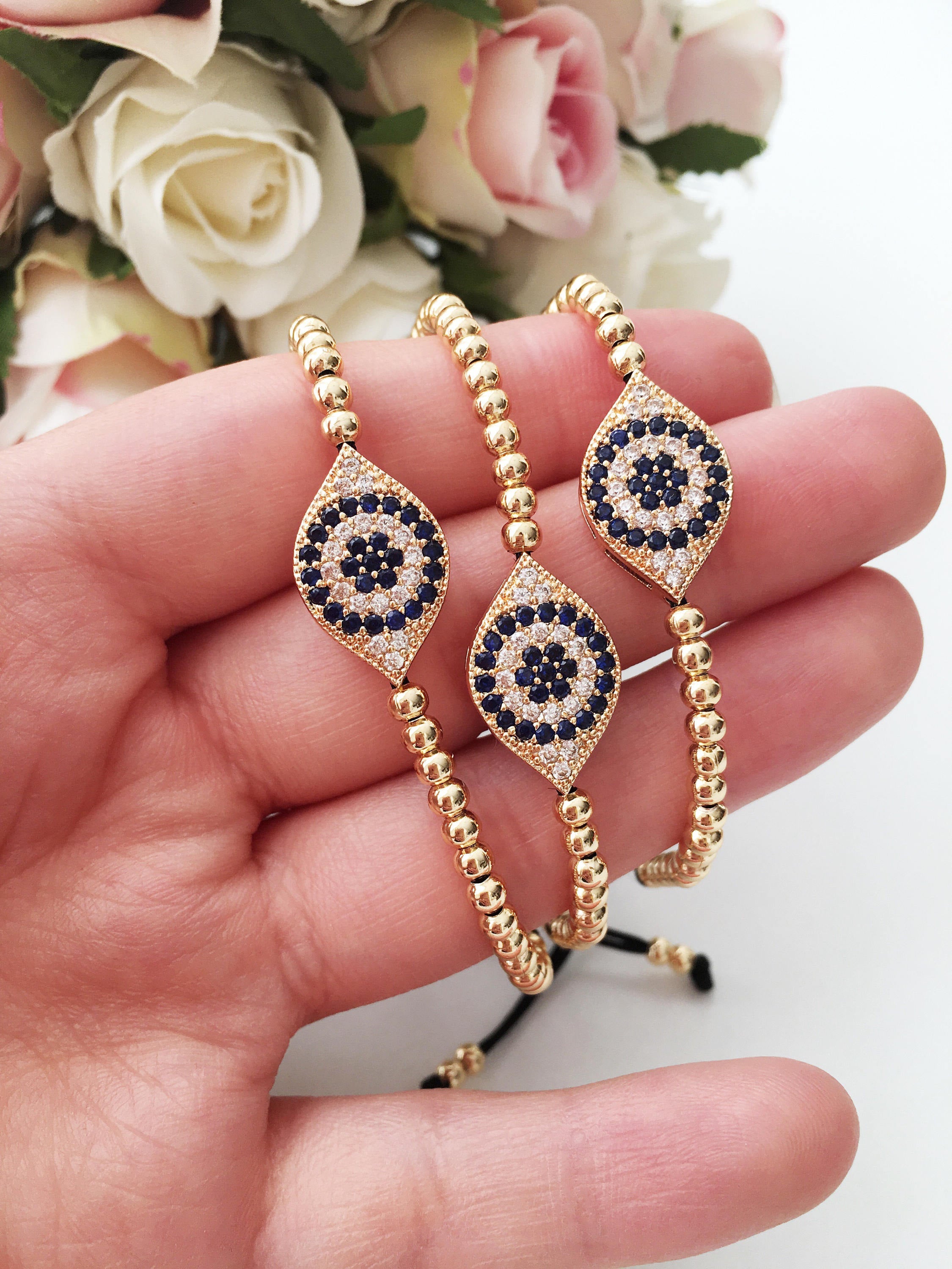 Gold Evil Eye Beaded Bracelet on a black string, showcasing its adjustable design and intricate evil eye charm.