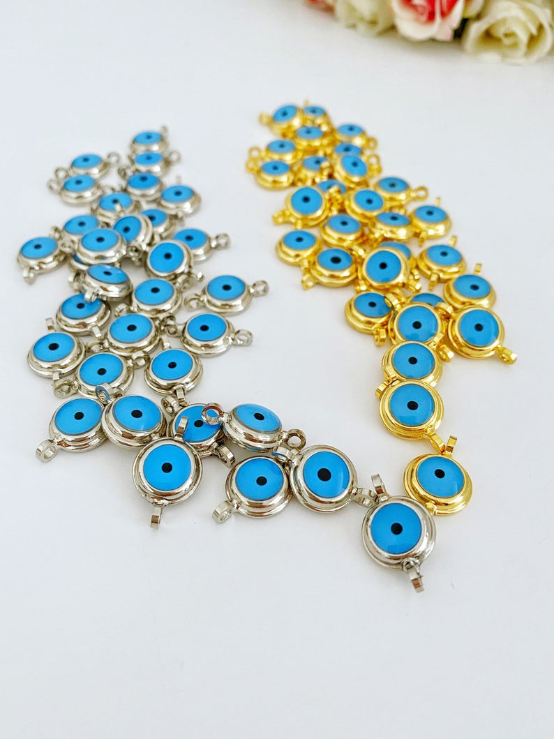 A collection of gold evil eye beads and connectors made from shiny gold plated brass, showcasing their intricate design and vibrant colors.
