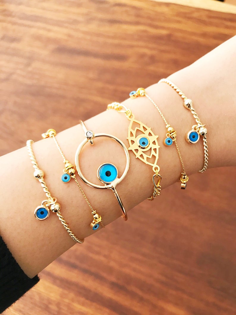 A beautiful Gold Evil Eye Bracelet made of tarnish-resistant stainless steel, featuring an adjustable design and available in four unique styles.