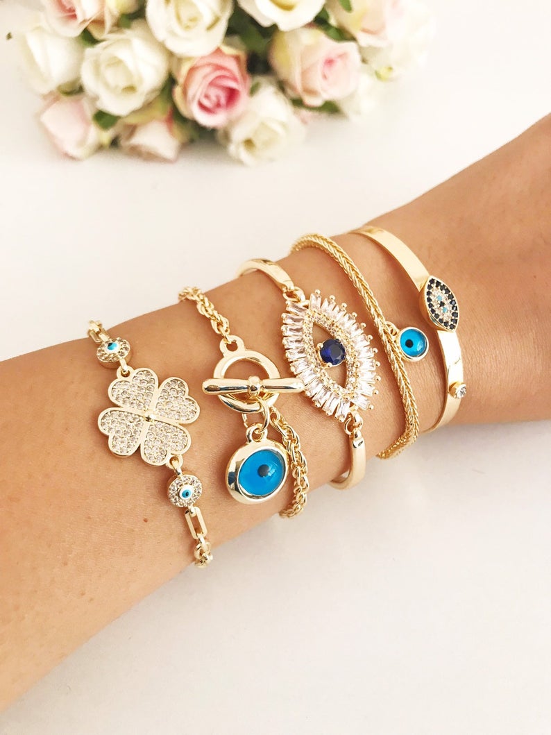 Gold Evil Eye Bracelet Set featuring adjustable bangles with blue evil eye beads, showcasing handmade craftsmanship and tarnish-resistant stainless steel.