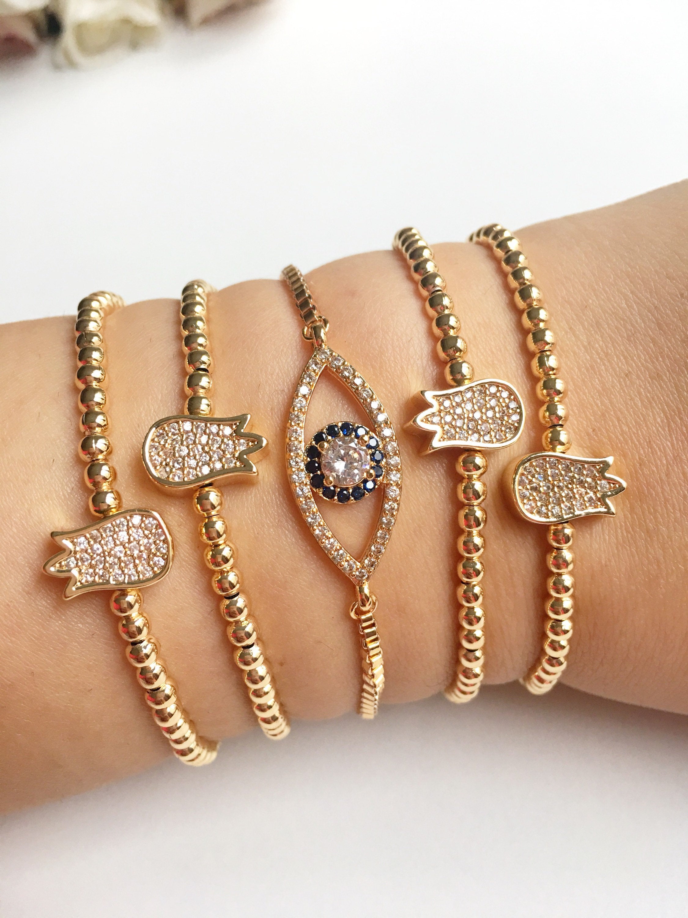 A beautiful gold evil eye bracelet featuring a tulip charm, showcasing intricate beading and an adjustable design for a perfect fit.