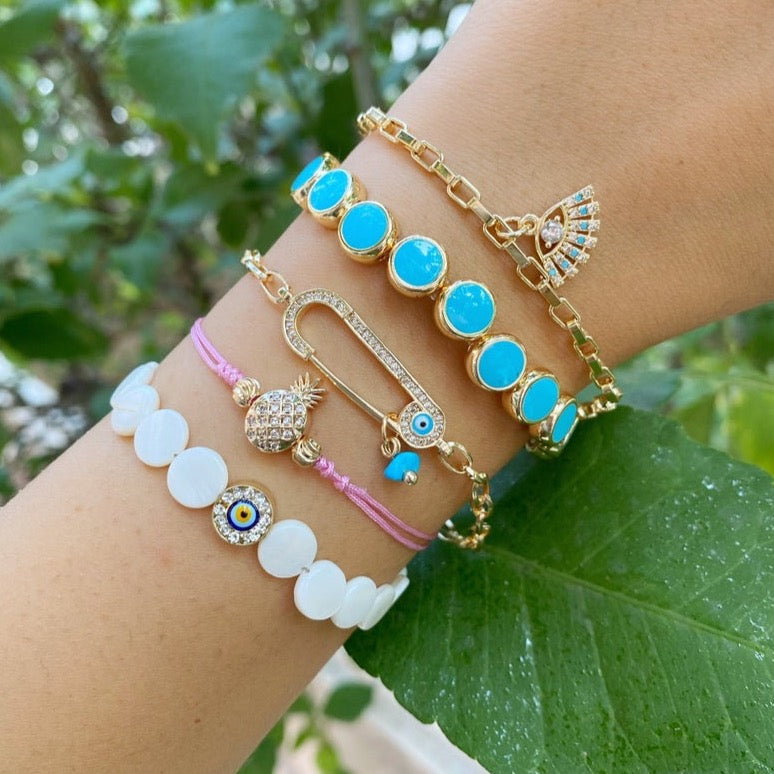 Gold Evil Eye Bracelet featuring turquoise beads and a safety pin design, showcasing its handmade craftsmanship and adjustable fit.