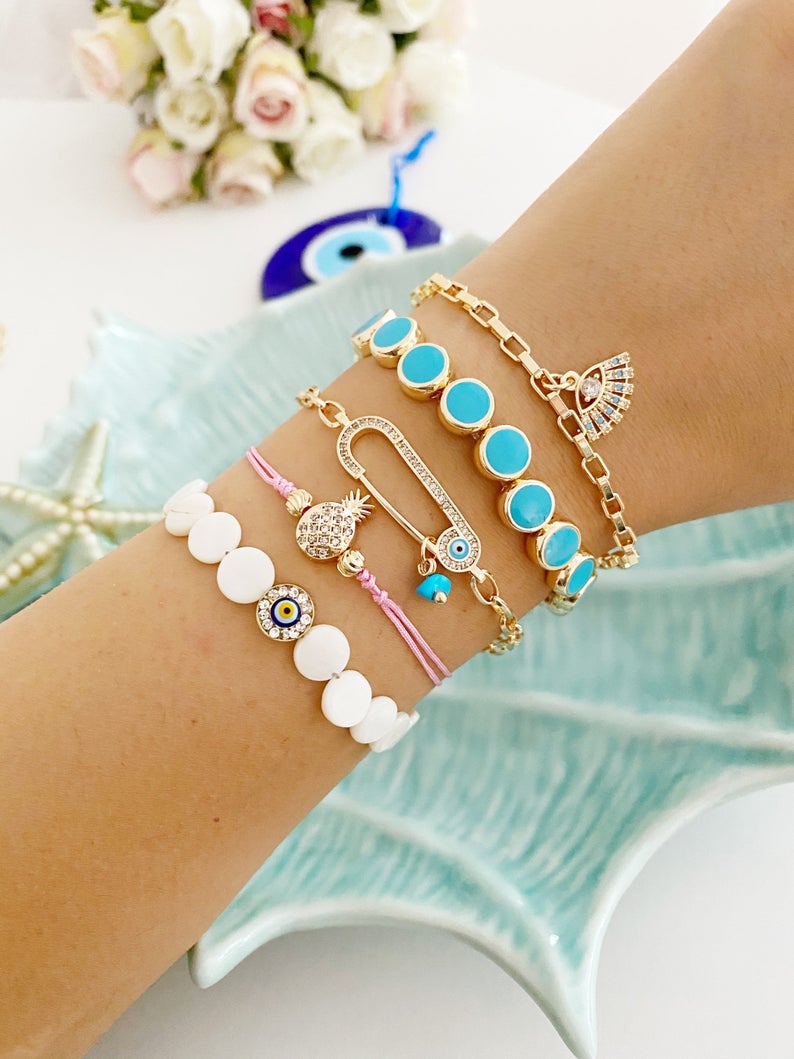 Gold Evil Eye Bracelet featuring turquoise beads and a safety pin design, showcasing its handmade craftsmanship and adjustable fit.